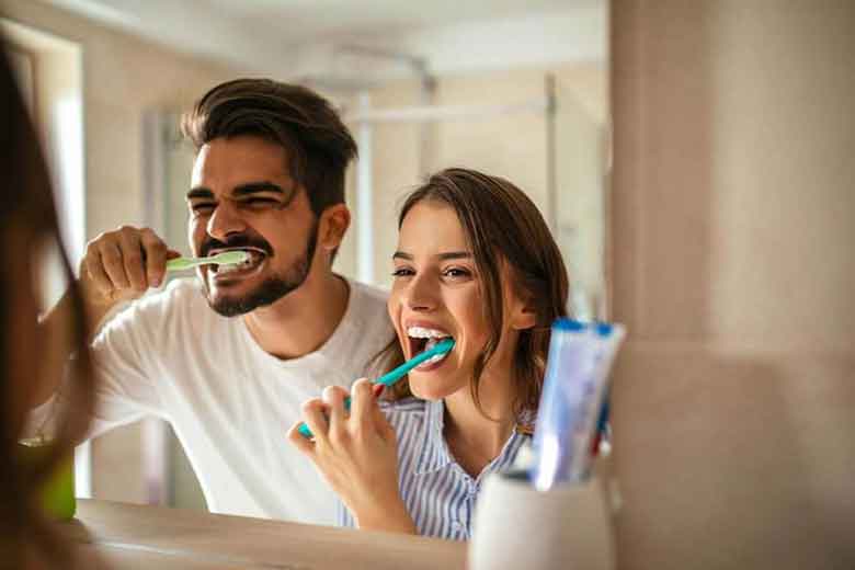 Couple Brushing the teeth in front of mirror