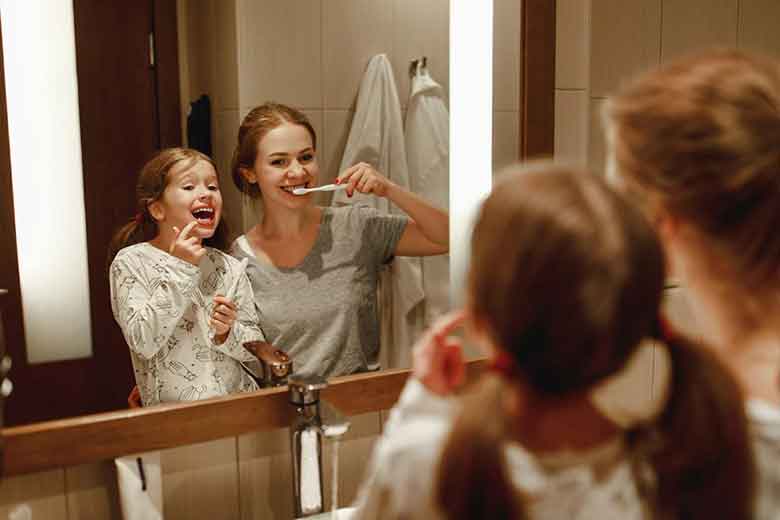 Two Girls brushing the teeth in front of mirror