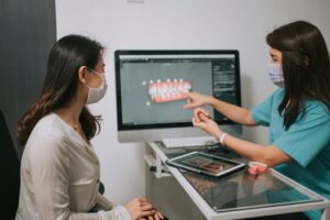 Dentist showing female patient dental implants on a screen in Parker, CO