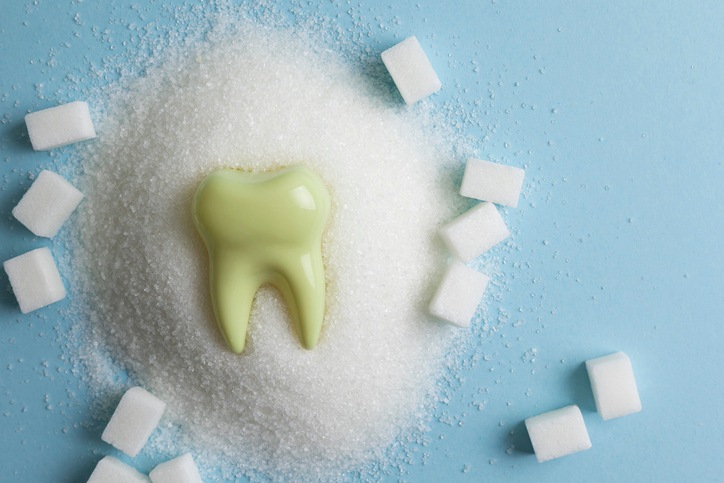 Image of a tooth decaying in a pile of sugar